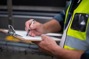 Factory Worker Maintaining Record on Clipboard